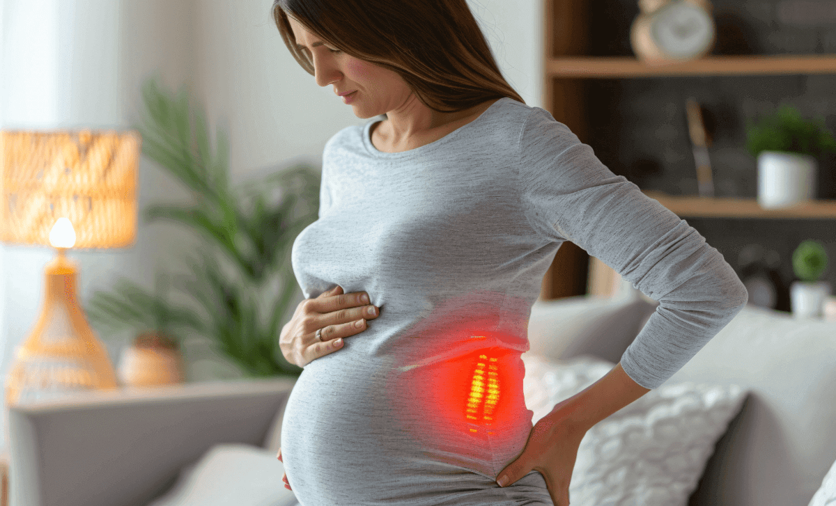 Pregnant woman holding her belly and lower back, experiencing round ligament or back pain—a common pregnancy symptom during the second and third trimesters.