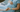 A pregnant woman in a hospital gown lying on a bed, gently cradling her baby bump while holding hands with a supportive partner or healthcare provider. 