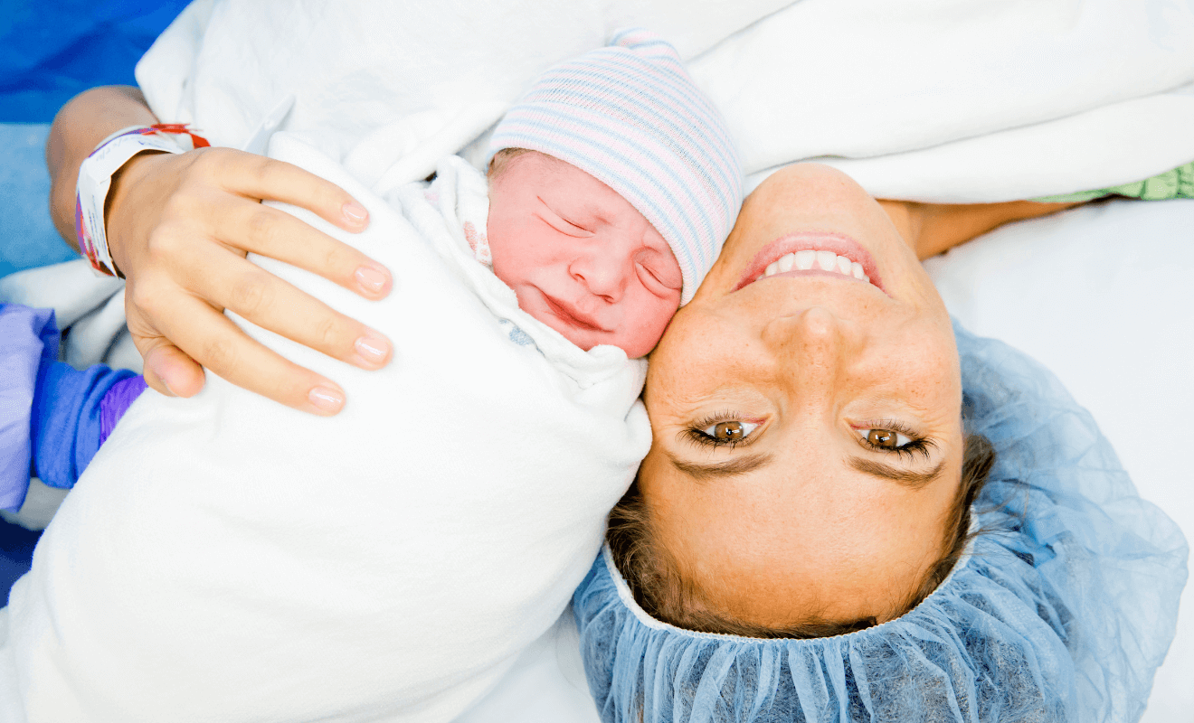 Smiling mom holding newborn after C-section, considering VBAC next