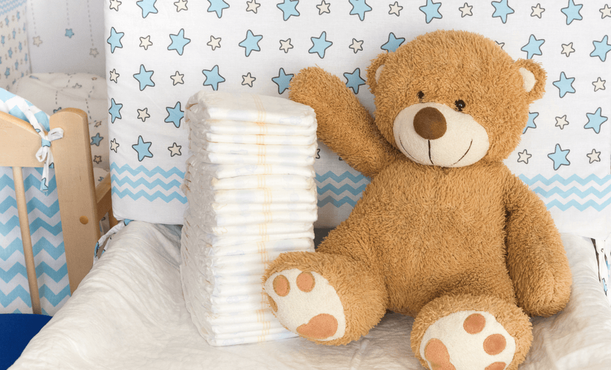 Newborn essentials checklist: Must-have baby items with diapers and a teddy bear in a cozy nursery.