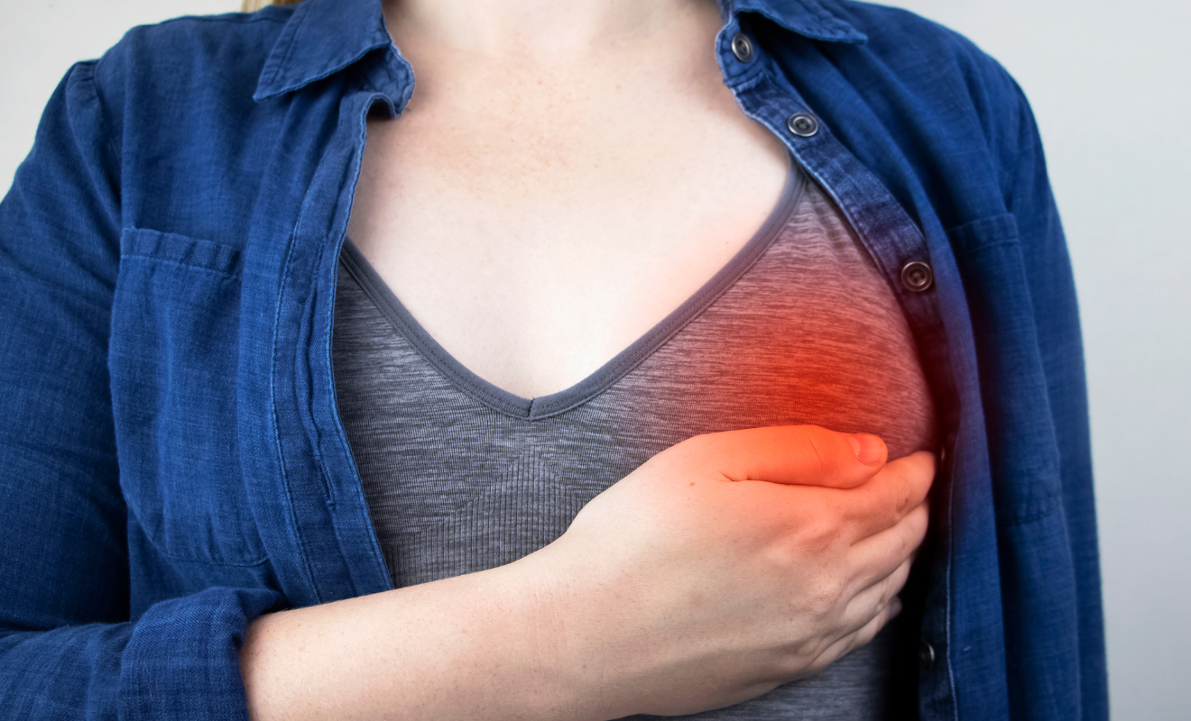 Image showing a woman holding her breast with a red highlight, depicting postpartum mastitis symptoms and breast pain