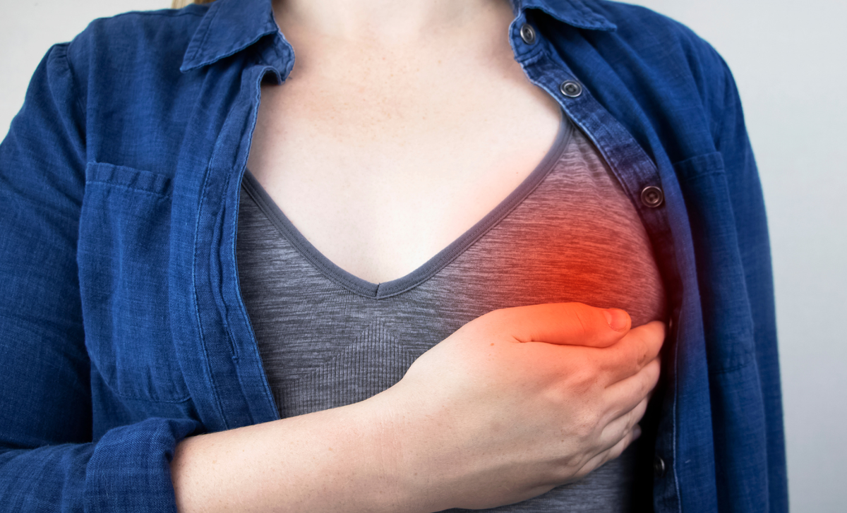 Image showing a woman holding her breast with a red highlight, depicting postpartum mastitis symptoms and breast pain