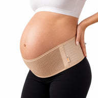 The AZMED maternity support belt in beige, worn under the bump and wrapped low across the hips, with the wearer's hand on her lower back.