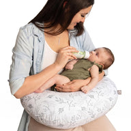 Mother bottle-feeding her newborn with the Boppy nursing pillow in the Gray Gentle Leaves print resting around her waist.