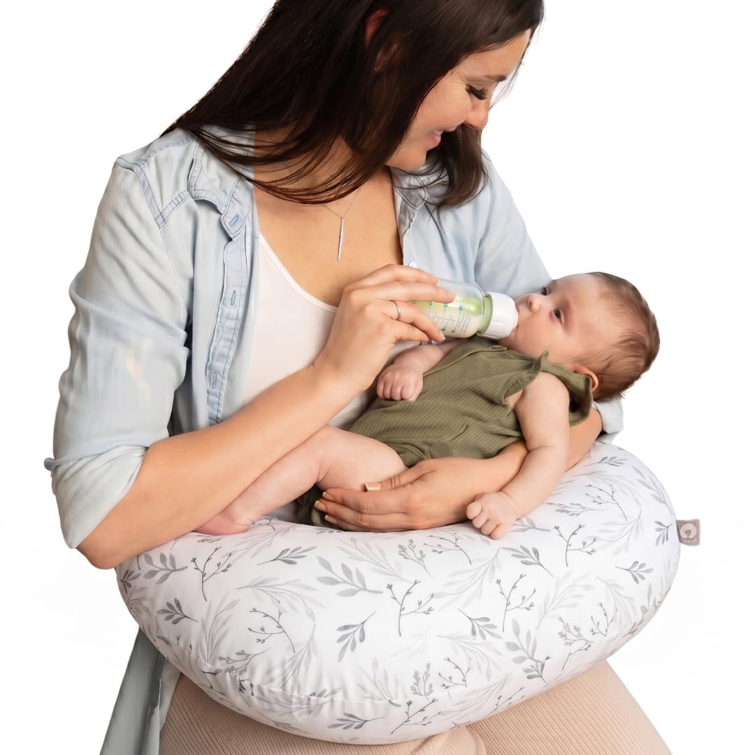 Mother bottle-feeding her newborn with the Boppy nursing pillow in the Gray Gentle Leaves print resting around her waist.