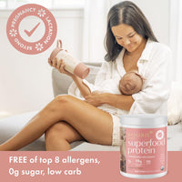 Mother breastfeeding her baby while holding a Boobie Body shaker, labelled free of the top 8 allergens, 0 g sugar and low carb