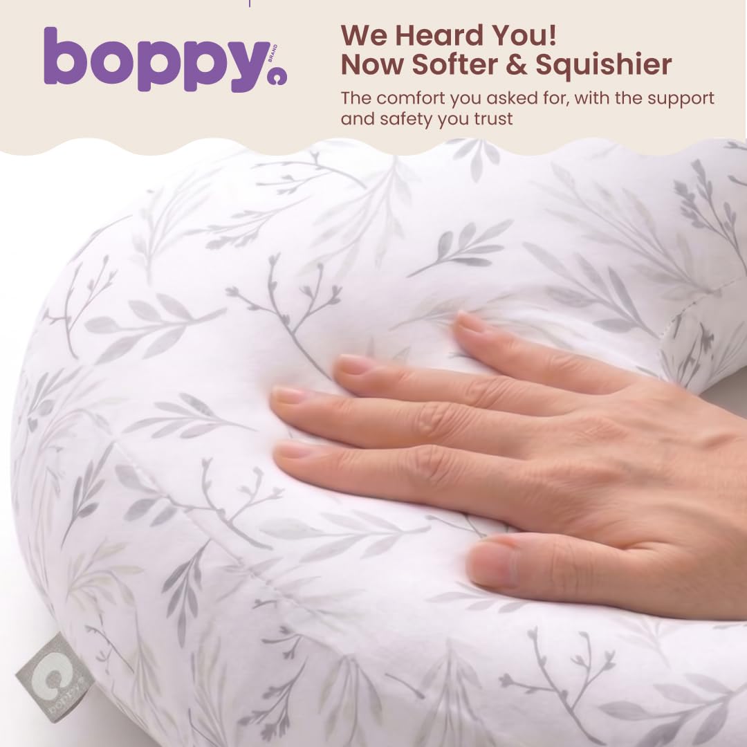 Hand pressing into the redesigned Boppy pillow beside Boppy's caption that it is now softer and squishier than the previous version.