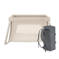 Newton Compact travel crib in Sand, set up, beside its grey backpack carry bag