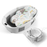 Collapsible baby bathtub with soft patterned insert and mesh storage bag, designed for easy baby bath time.