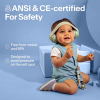 Baby sitting up wearing sage green Alpine Muffy Baby earmuffs, with notes that they are free from metals and BPA and designed to avoid pressure on the soft spot