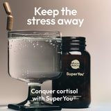 Stress relief supplements for women by Moon Juice SuperYou in a glass with water.