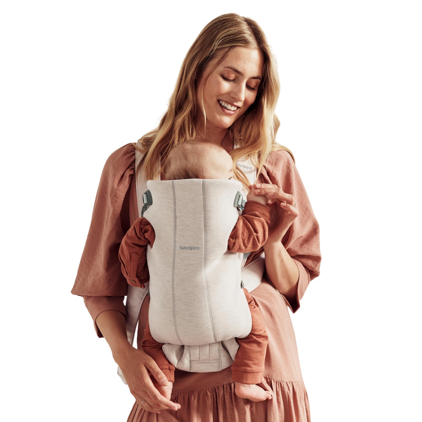 Mom using a baby carrier with her newborn, showcasing BabyBjörn Mini design for comfort and support.