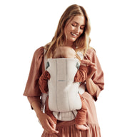 Mom using a baby carrier with her newborn, showcasing BabyBjörn Mini design for comfort and support.