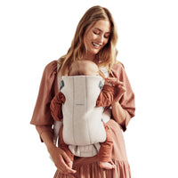 Mom using a baby carrier with her newborn, showcasing BabyBjörn Mini design for comfort and support.