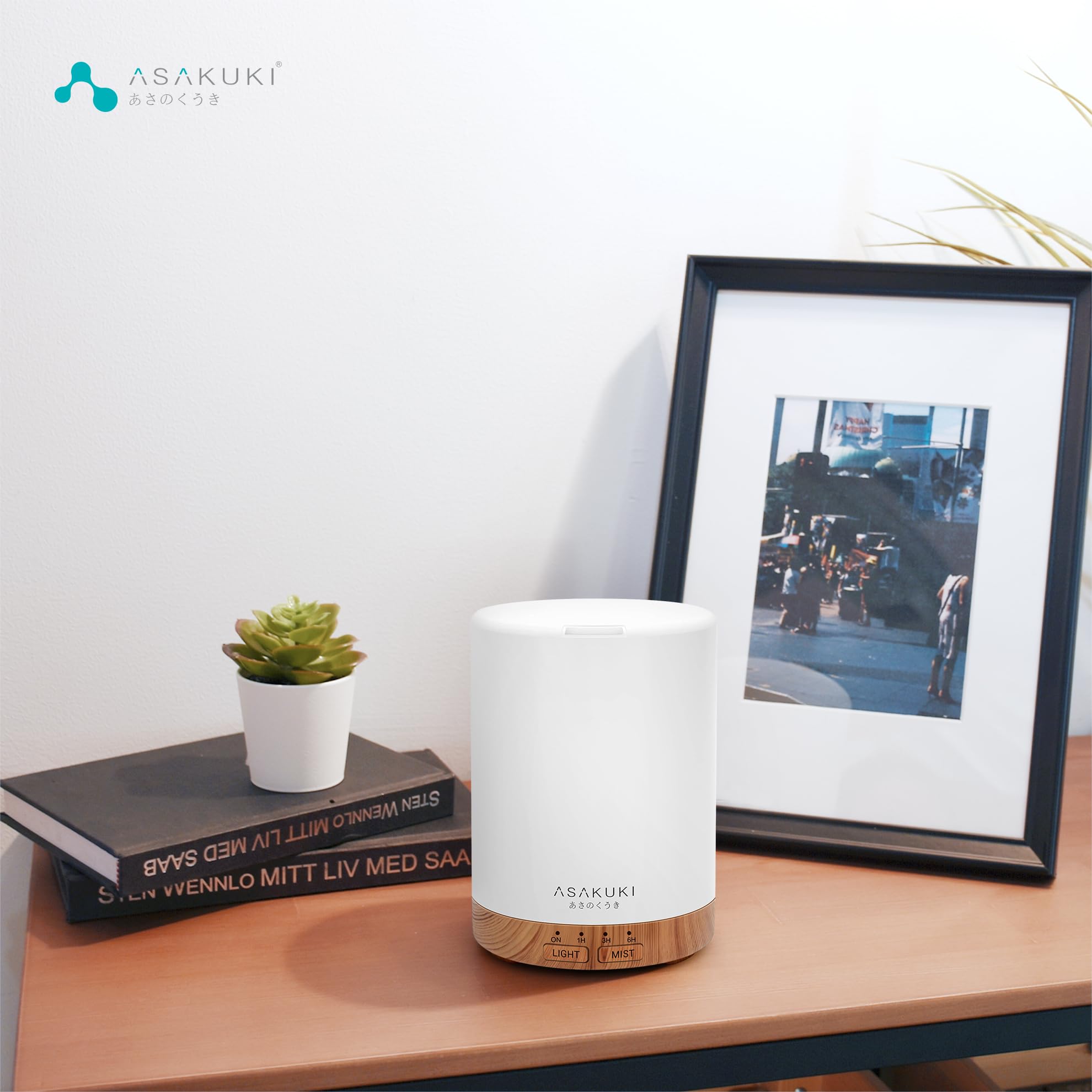 Essential oil diffuser on a wooden table next to a picture frame and plant, promoting relaxation and calmness.