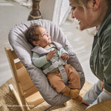 Baby high chair Stokke Tripp Trapp with newborn set, showcasing a smiling baby and caregiver interaction.