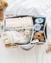 Lily Miles baby diaper caddy filled with diapers, baby toys, and essentials for newborn care.