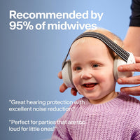 A parent fitting white Alpine Muffy Baby earmuffs onto a smiling toddler in a lilac knitted sweater