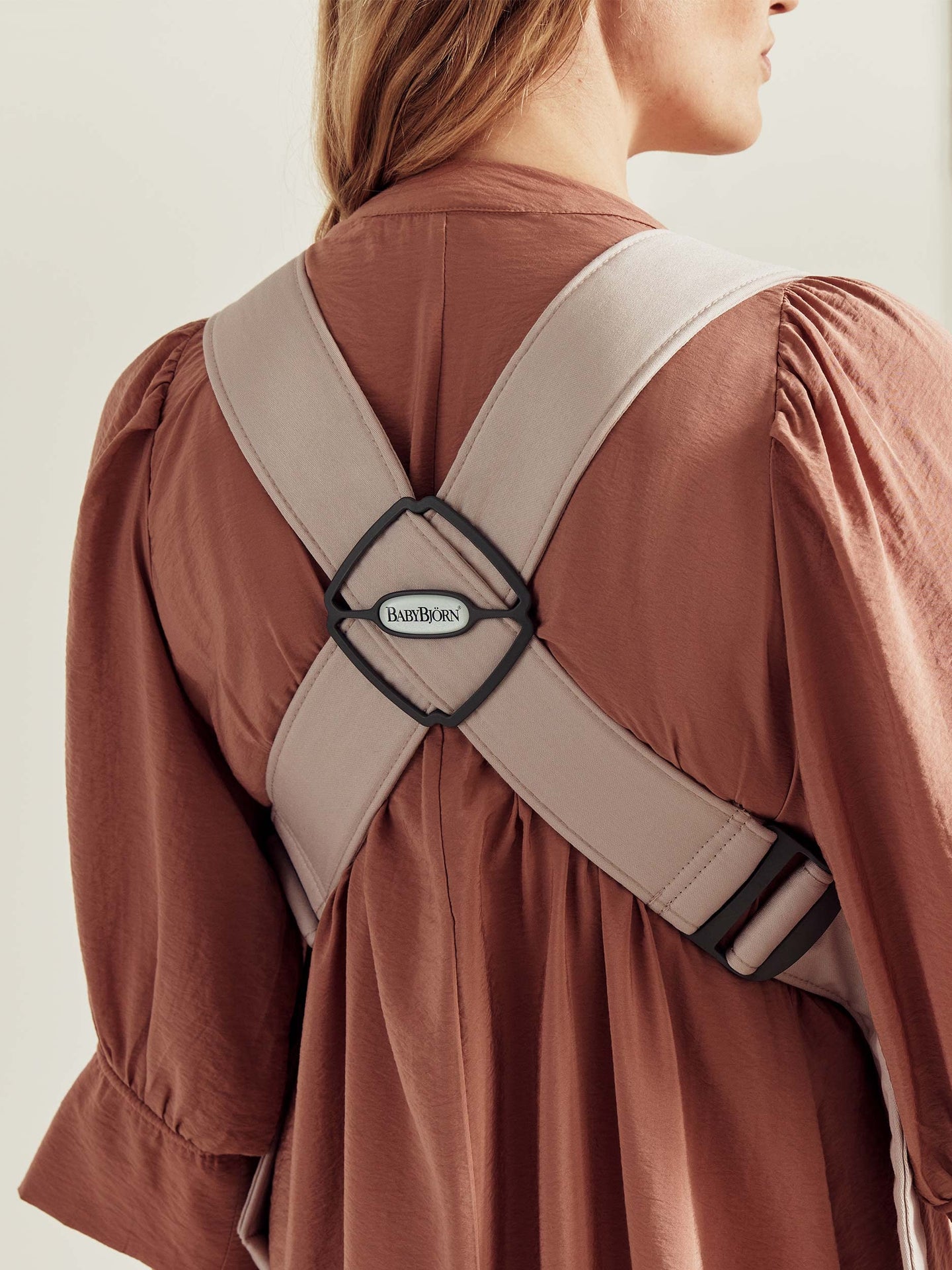 Back view of a woman wearing the BabyBjörn baby carrier, highlighting the ergonomic design and adjustable straps.