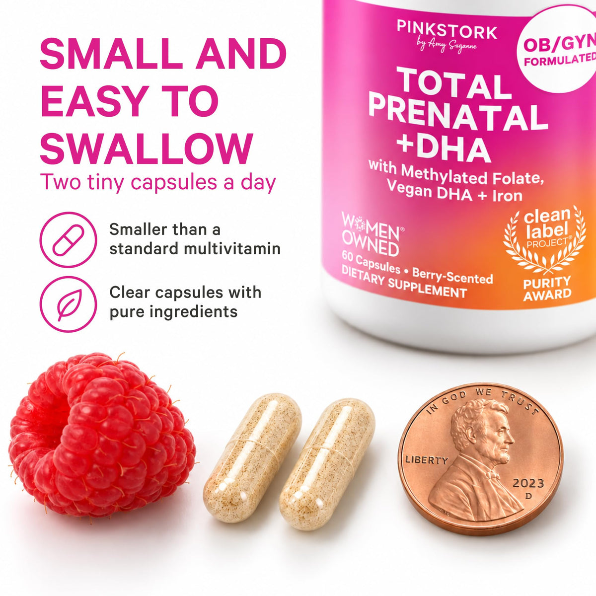 Two small Pink Stork prenatal vitamin capsules next to a penny and a raspberry, showing the capsule size