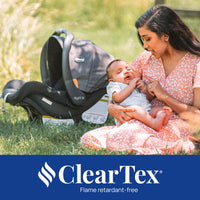 Mom interacting with baby next to Chicco KeyFit 30 infant car seat in a grassy area.