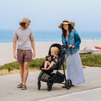 Mompush Wiz convertible bassinet stroller in use at the beach with family, ideal for newborns and toddlers.