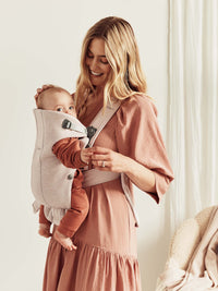 A mother using the BabyBjörn Mini newborn baby carrier to hold her baby comfortably.
