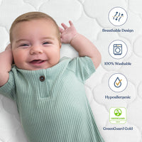 Happy baby lying on a crib mattress with features showing breathable design, 100% washable, hypoallergenic, and GreenGuard Gold certification.