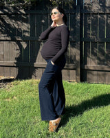 Maternity leggings model showing over belly support in a sunny outdoor setting, perfect for comfort during pregnancy.