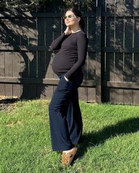 Maternity leggings model showing over belly support in a sunny outdoor setting, perfect for comfort during pregnancy.